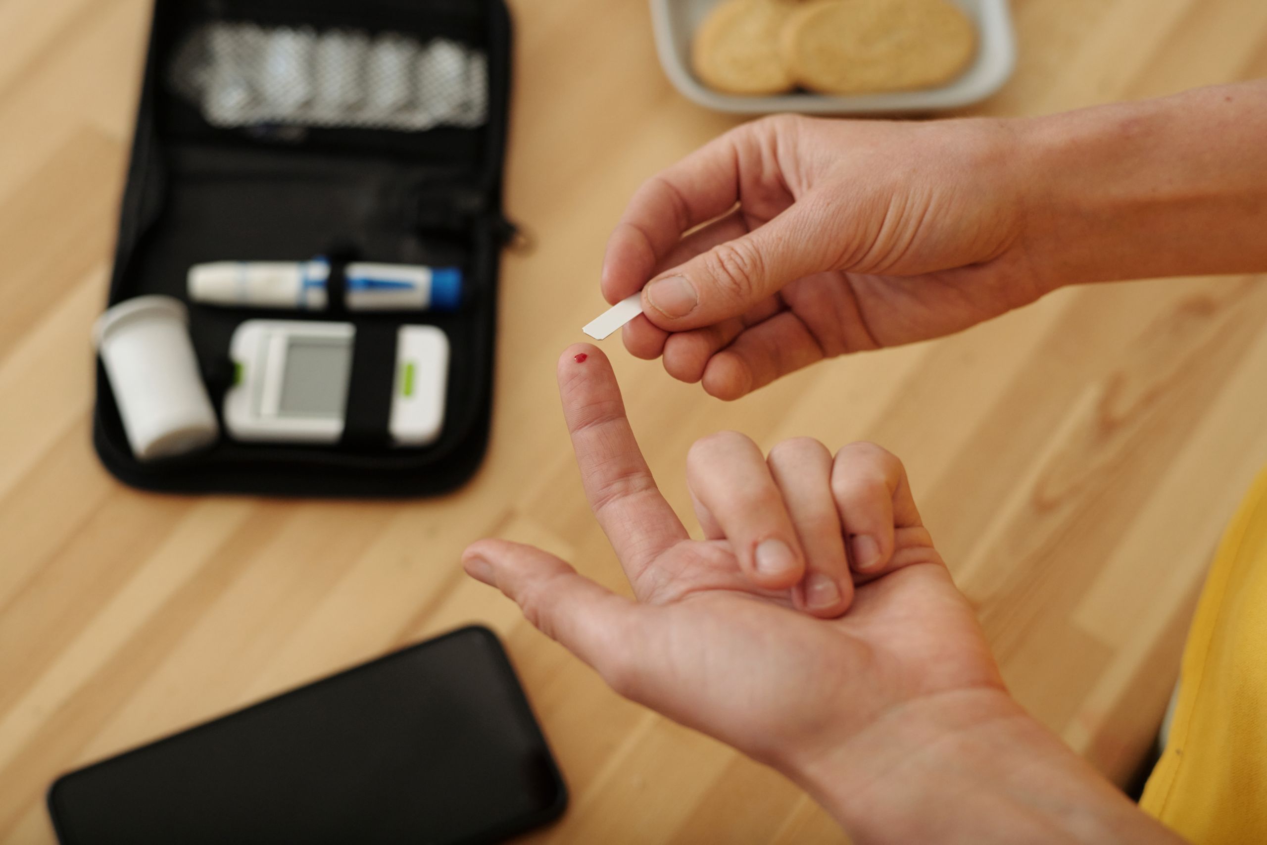 Person with diabetes using blood test strips to monitor glucose levels